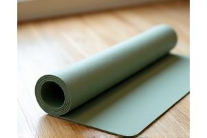 Premium, thick yoga mat unrolled on a wooden floor.